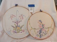 Two embroidered pieces - one floral bouquet with butterflies, one girl in a dress, both in wooden hoops