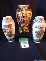 Three Asian style vases shown together - one large center vase and two smaller matching vases on either side. Detailed colorful traditional paintings on porcelain ceramic.