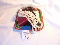 Overview photo showing layered white faux pearl and dark bead necklaces on a tray