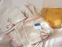 Photo showing white and off-white table linens with floral embroidery and lace edges folded together.