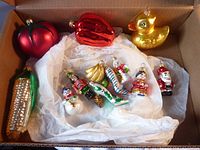 Photo showing assortment of large and miniature figural glass Christmas ornaments including tomato, red pepper, duck, and corn on the cob.