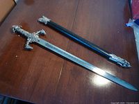 Full view of the decorative sword and matching black scabbard placed on a wooden surface.