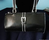 Front view of black compact purse showing silver buckle detail and embossed KS18 logo