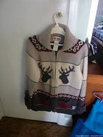 Full front view of sweater hanging on hanger showing pattern, zipper, and collar.