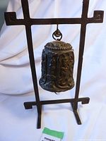 Overall view of the metal gong hanging on its iron stand, showcasing the entire framed structure with the gong centered.