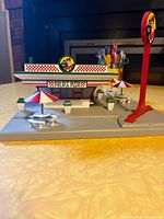 Front view of the Palace Pizza model showing the building facade with Palace Pizza signage, outdoor tables with umbrellas, and standing sign.