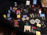 Photo showing the full collection of various pierced earrings arranged on a black surface, highlighting different styles, sizes, and materials.