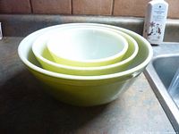 Set of 3 Pyrex bowls nested inside each other on a kitchen counter, showing the green exteriors and white interiors.