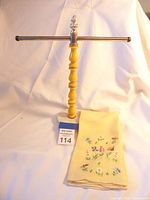 Vintage yellow towel stand against neutral background, showing full stand with marble base and folded towel in front.