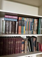 Full shelf view showing multiple rows of antique and vintage books including thick leather-bound volumes and dust-jacketed Reader's Digest condensed books.