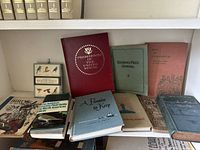 Photo showing collection of twelve antique and old books arranged on a shelf. Includes hardcover hymnals, vintage bird guides, history and literature books.