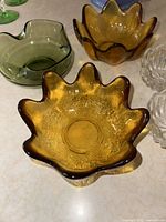 Amber Blenko lotus-shaped glass bowls, green abstract glass bowl and clear patterned glass bowls on countertop.