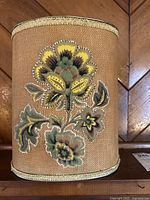 Side view showing raised fabric floral applique on burlap-covered metal garbage can