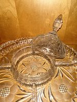 Close-up showing detailed pressed floral and geometric patterns on a covered serving dish with handle and finial lid.