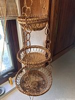 Close-up photo of the three hanging baskets showing woven wicker material and chain links connecting the baskets.