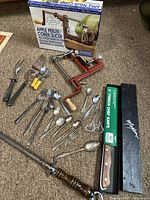 Full lot view showing apple peeler with box, knives, spoons, forks, sharpener, and pie server on carpet.