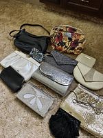 Overview of 10 ladies purses and bags of different styles, colors, and materials laying on carpet floor.