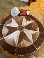 Photo showing round patchwork cowhide rug, white pierced cowboy hat, brown leather gloves, red bandana, Brut aftershave, and boxed vintage handkerchiefs