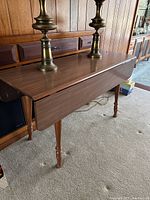 Overhead and side views of midcentury drop leaf laminate top table showing the extended leaves, solid wood frame and turned legs.