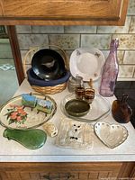 Full view of all items arranged on a countertop, showing the variety including paintings, bottles, dinnerware, and basket.