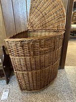 Full side view of the quarter round wicker hamper with lid open showing interior compartment.