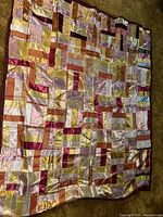 Full view of the silk crazy quilt showing patchwork of rectangular silk fabric pieces in varied warm tones.