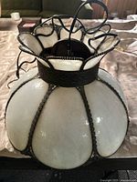 Top-down view showing scalloped white slag glass panels and twisted floral metal framing on hanging lamp.