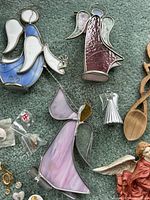 Stained glass angels in various colors and designs displayed on green carpet, showing detailed metal frames and wings