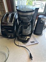Photo of the three kitchen appliances together: T-FAL Avante High Speed toaster, Black+Decker coffee maker, and Hamilton Beach can opener with power cords visible.