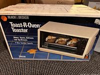 Photo of front of sealed box showing Black & Decker Toast-R-Oven Toaster TR020 with image of toaster oven and product functions.