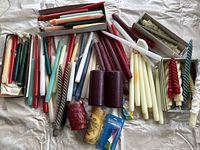 Overview of the large assortment of used candles in multiple colors, shapes and sizes spread on a surface.