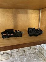 Two vintage Avon train-shaped cologne bottles, showing both items on a wooden shelf.