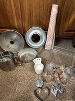 Wide shot of entire vintage baking collection showing sifter, cake pans, pastry mat, measuring cups, glass baking dish, and cookie cutters.