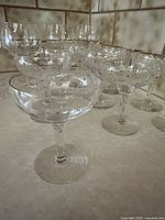 Grouped photo showing 6 plain wine glasses and 9 etched cocktail glasses arranged on a counter.