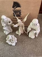 Four porcelain nativity figurines displayed together, including Mary, Joseph, Christ Child in floral cradle, and Angel Gabriel with wings, all in original Boehm box background.