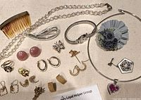 Overview photo showing all vintage jewelry items laid out on fabric including earrings, brooches, necklaces, and a hair comb