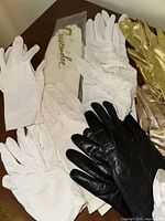 Gloves of various materials including white cotton, lace, gold metallic, light pink leather, black leather, black satin with bead trim.
