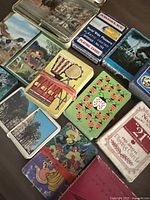 Photo of multiple decks of vintage playing cards with various designs including landscapes, musical instruments, animals, and buildings.