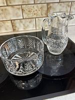 Pitcher and bowl set on black surface with tiled background, showing overall shape and design