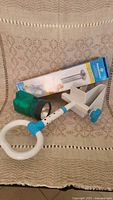 Photo showing drive medical grab bar box, vintage green flashlight and blue white bathtub handle items on cloth.