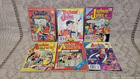 Photo showing six vintage comic books with various cover art including Archie, Jughead Jones, and Laugh Comics Digest.