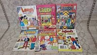 Six vintage Archie comic books arranged on carpet background, featuring Laugh Digest and Jughead's Double Digest titles.