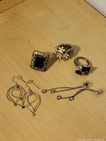 Overview photo showing all pieces of costume jewelry including rings and earrings on a wooden surface.