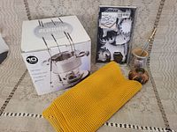 Photo of the entire lot showing fondue set box, cookie cutters on plastic blister, three yellow rubber mats, and two yerba mate cups with straw.