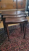 Photo showing the three wooden nesting tables arranged side by side, highlighting the carved legs and dark wood finish.
