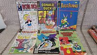 Photo of 7 vintage comic books laid out on a surface showing front covers including Richie Rich, 3 different Donald Duck comics, Bugs Bunny, Scamp, and Mighty Mouse.