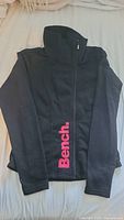 Black Bench zip-up sweatshirt with pink Bench logo on left bottom side laid flat.