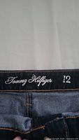 Close-up of Tommy Hilfiger brand label and size 12 on inside waistband of denim jeans.
