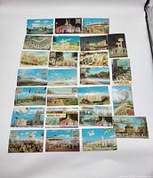 Photo showing all 28 postcards laid out in rows on a white surface, featuring colorful views of the fair's landmarks and attractions