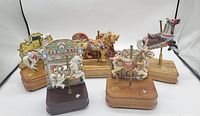 Five carousel animals made of porcelain and wood shown together, mounted on wooden bases with music box mechanisms.
